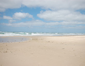 Bred sandstrand med blå himmel og Vesterhavet