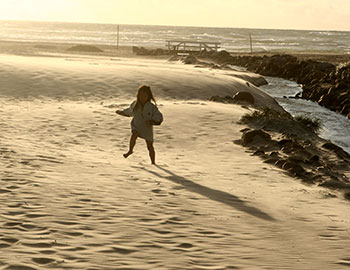 Lille pige løber på stranden ved Løkken