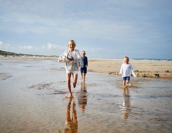 Tre glade børn leger på stranden